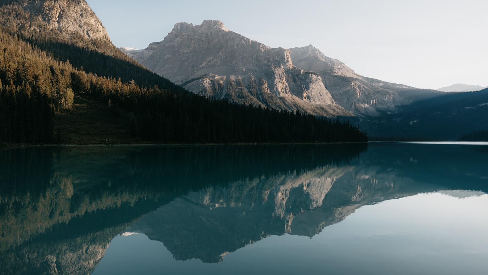 Lago calmo ao amanhecer refletindo montanhas — a serenidade de acalmar a mente