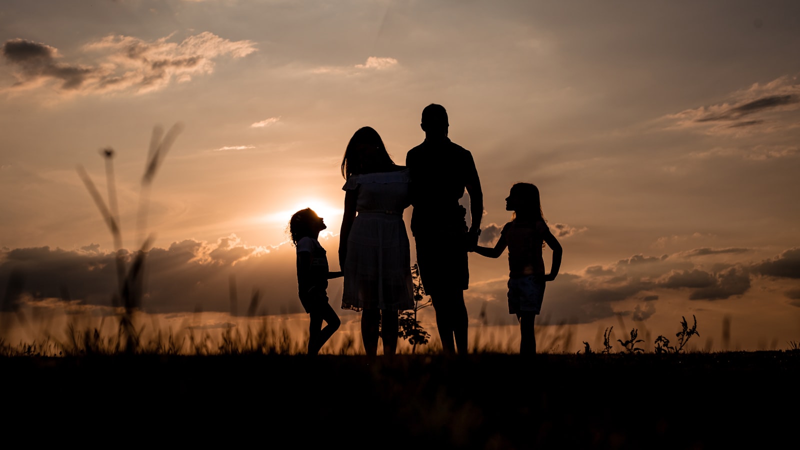 Família reunida em um campo aberto ao entardecer — o calor que a gentileza espalha
